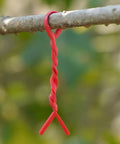 Top Shelf Flat Iron Wire Twist Ties For Garden Vine Support And Plant Securing Reusable Red Gardening Strips With Sturdy Metal Core hanging on a branch.