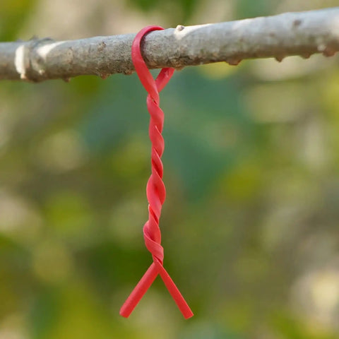 Top Shelf Flat Iron Wire Twist Ties For Garden Vine Support And Plant Securing Reusable Red Gardening Strips With Sturdy Metal Core hanging on a branch.