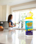 Front view of Invisible Glass Glass Wipes bottle with yellow cap on kitchen counter; 40 pre-moistened wipes.