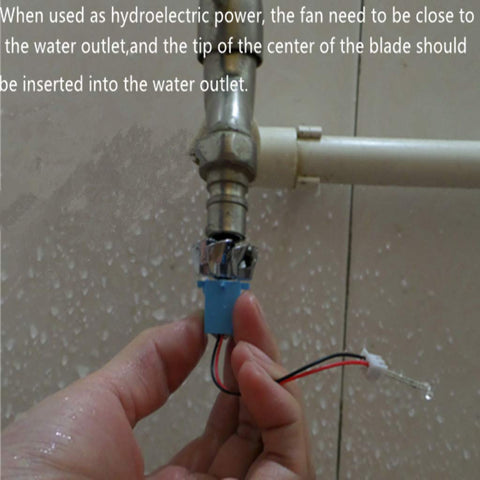 Hands holding a component of the Wind Hydroelectric Generator Model For STEM Classrooms, Hands On Renewable Energy Teaching Kit With Quick Assembly Parts To Demonstrate AC Wind Power Gen Principles near a water outlet, demonstrating assembly.