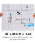 Hands holding Magnetic Project Mat And Screw Organizer Pad For Electronics Repair, with metal screws and fasteners organized on surface.