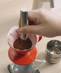 Premium Retractable Espresso WDT Tool All Stainless Steel Coffee Distribution Needle used on coffee grounds in red filter.
