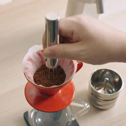 Premium Retractable Espresso WDT Tool All Stainless Steel Coffee Distribution Needle used on coffee grounds in red filter.