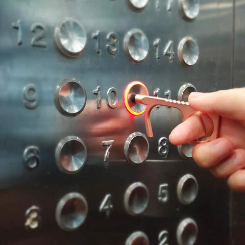 Person using No Touch Door Opener Tool With Stylus And Button Pusher on elevator button, rose finish