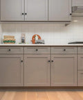 18 Pack 1-1/5 Inch Matte Black Round Cabinet Knobs Zinc Alloy Heavy Duty Pulls on kitchen cabinets with gray finish.