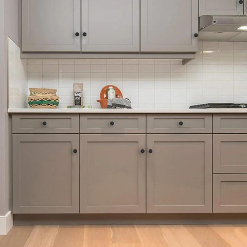 18 Pack 1-1/5 Inch Matte Black Round Cabinet Knobs Zinc Alloy Heavy Duty Pulls on kitchen cabinets with gray finish.