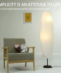 Foldable Rice Paper Floor Lamp Shade In Minimalist Modern Style next to chair, lightweight and durable, about 43.3 cm tall.
