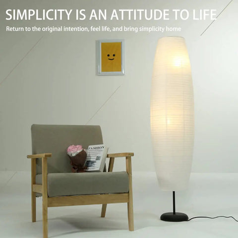 Foldable Rice Paper Floor Lamp Shade In Minimalist Modern Style next to chair, lightweight and durable, about 43.3 cm tall.