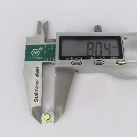 Caliper measuring 8mm base of a 10 Pack White T3 Neo Wedge 3030 LED Bulb for car dashboards and HVAC controls