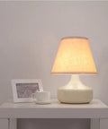 Barrel White Small Lamp Shade For Table Lamps Replacement 5x9x7 Inch Fabric Cloth Spider Model on a lit table lamp in a living room.