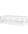 Totally Built Tough Twin Floor Bed With Montessori Design And Complete Safety Guardrails Plus Easy Access Door For Kids, Solid Wood Low Profile Slatted Frame In Fresh White viewed from the side.