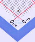 Close-up of a gold ESD diode DFN0603-2 ESD7381MUT5G on a gridded background