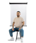 Retractable White Photo ID Backdrop For Passport Photos, Wall Or Ceiling Mount, 36 Inch Wide Screen, person sitting in front