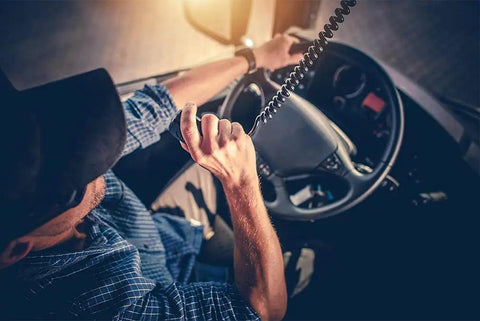 Driver using 4 Pin CB Radio Microphone Replacement with Ergonomic Grip, Rugged Build, Clear Sound, 8 Foot Coiled Cord in a truck.
