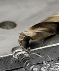 M42 cobalt twist drill bit, gold-colored, cutting into a metal workpiece (close-up).