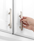 Hand gripping 20 Pack 3 Inch Brushed Nickel Kitchen Cabinet Pulls Satin Silver Handles For Cabinets And Furniture Smooth Rounded Corners Prevent Snags Easy Grip Beefy Solid Metal Hardware For Kitchen Bedroom Dresser Cupboard on white cabinet doors.