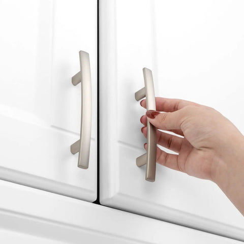 Hand gripping 20 Pack 3 Inch Brushed Nickel Kitchen Cabinet Pulls Satin Silver Handles For Cabinets And Furniture Smooth Rounded Corners Prevent Snags Easy Grip Beefy Solid Metal Hardware For Kitchen Bedroom Dresser Cupboard on white cabinet doors.