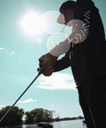 Person fishing with Laguna LT Spinning Reel 3 Plus 1 Ball Bearings 5.3 to 1 Gear Ratio with Auto Tournament Drag near lake.