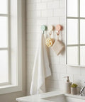 15 Pack Self Adhesive Wall Hooks With Hella Strong Grip No Drilling Damage Free Mounting For Towels Keys And Flatware Decorative Cutesy Style Perfect For Bathroom Office Or Closet Super Easy Setup And A Surefire Storage Winner with white towel and decorative items.