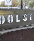 A metal sign with 'TOOLSTODAY' cut out, displayed outdoors; CNC machining example.