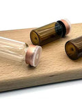 Front view: GISUREM 10ml glass vials, one clear and two amber borosilicate with pink flip-off caps on a wooden surface.