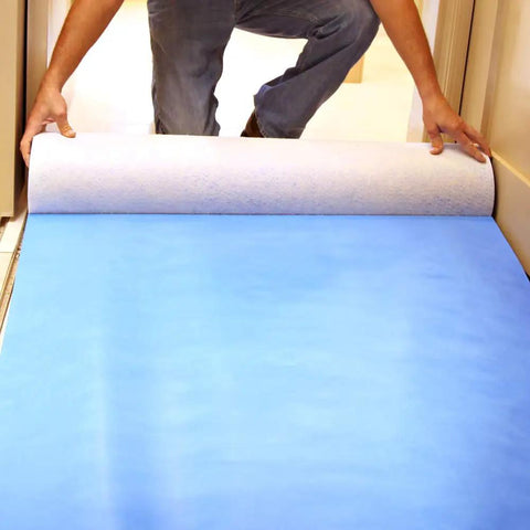 Person unrolling 24 Inch By 100 Foot Surface Protector For Hardwood Vinyl Tile Marble And Stairs Waterproof Reusable Pad