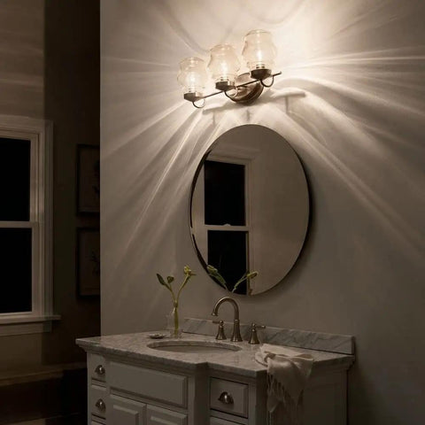 Janiel 24 Inch Three Light Vanity Light With Clear Glass Shades In Classic Bronze Finish Above Mirror in Bathroom