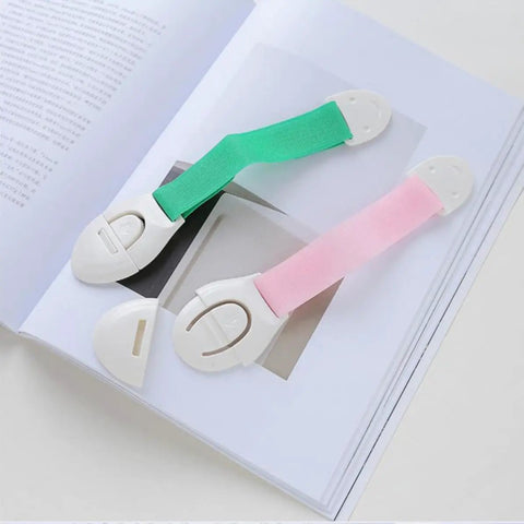 Stick On Cabinet Locks 10 Pack Self Adhesive PP Material Kid Proof Latches For Cabinets Drawers Fridge And Toilet Doors Easy Install Strong Hold Simple Design Assorted Colors in green and pink on a book.