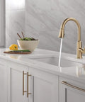Modern Single Hole Kitchen Faucet With Slick Pull Down Sprayer Brushed Gold Finish, water flowing from spout in stylish kitchen.