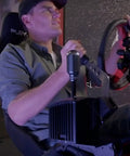 Man using Universal Sim Racing Gear Shifter and Handbrake Mount Adjustable Cockpit Bracket in gaming seat setup.