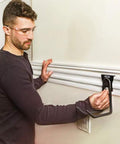 A man installs a VersaTrack Garage Storage Rail With Twenty Piece Mounting Accessories For Drywall Studs And Masonry on a garage wall.