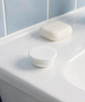 5pcs Silicone Bathtub Drain Plug Cover White for 30-31mm Holes on a bathroom countertop next to soap.