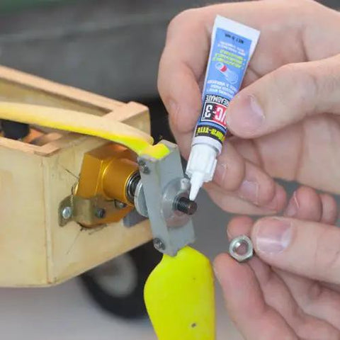 Person applying threadlocker on a bolt with a nut and a yellow propeller in view, related to Pro Grade Torque Screwdriver With One Quarter Inch Drive Precise 10 To 70 Inch Pounds Adjustable Torque Laser Calibrated For Tightening And Loosening Small Screws Includes Threadlocker Tube.