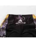 Back view of cycling shorts with colorful design and logo, featuring floral graphics and black-yellow pattern detailing.