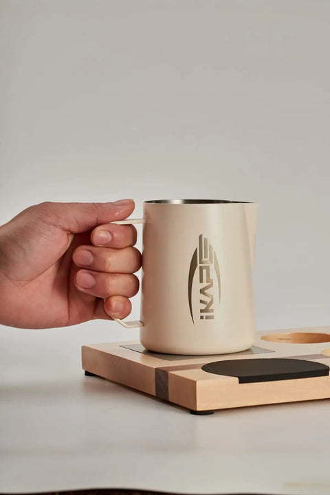Person holding latte art pitcher on espresso tamper base and accessories organizer in natural walnut