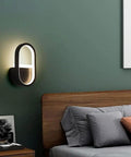 Modern Geometric Wall Sconce With 15 Watt Led Bulb And Sleek Aluminum Iron Frame For Bedroom Nightstand Setup Or Living Room Accent Lighting Super Chic Home Vibes Easy Wall Mount Soft Glow Lamp mounted beside a bed on a green wall.