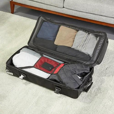 Amazon Basics 35-inch black rolling duffel bag opened to reveal packed clothes and interior pockets.