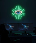Neon Evil Eye Wall Decor Sign With Dimming LED Green Goth Eyes Bohemian Witchy Bedroom Wall Art USB Powered Neon Light For Meditation Cozy Vibe Dope Gift Modern Home Christmas Decor glowing above a desk setup with monitors in a dark room.
