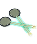 Two round FSR402 pressure sensors with green flex leads and gold contact pads