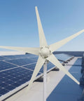 1200W Wind Power Generator Kit With 12V 24V Start 2.5 Meters Per Second Turbine Easy Install Charging Controller DC 27 To 54V For Home Farm Factory RV Boats Warehouse And Camps Off Grid Wind Turbine System installed on a rooftop with solar panels.