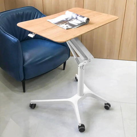 Hella Stable Mobile Standing Desk Featuring Instant Gas Spring Lift And Smooth Glide Rollers For A Total Game Changer Home Office Upgrade Or Flexible Workspace Setup In Clean Black next to a blue chair.