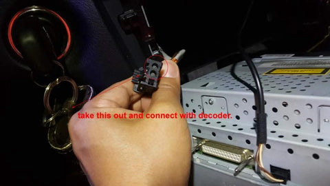 LEXXSON optic fiber decoder connector, black, held by hand near a car stereo head unit.