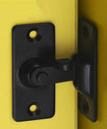 Close-up of a black 90 Degree Latch Door Bolt For Sliding Doors And Cabinet Doors Premium Stainless Steel Lock installed on a yellow surface.