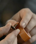 Close-up of a person applying Tank Bond Thread Stopper Tape Orange For Interior And Exterior Use Quick Fix For Loose Screws Instantly No Dry Time.
