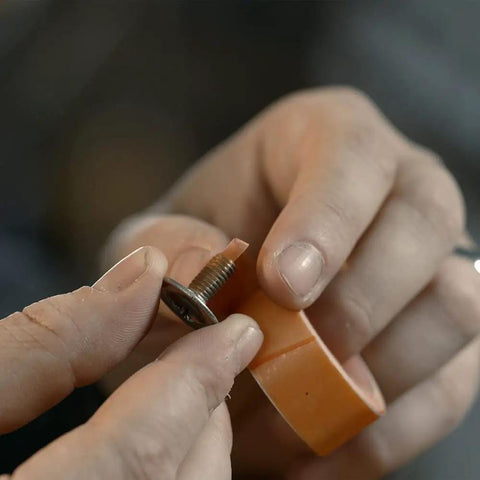 Close-up of a person applying Tank Bond Thread Stopper Tape Orange For Interior And Exterior Use Quick Fix For Loose Screws Instantly No Dry Time.