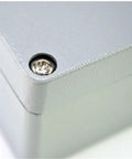 Junction box corner close-up; gray cast-aluminum enclosure with a recessed screw