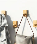 Modern Wall Mounted Coat Rack With Smooth Beige Finish Sleek Space Saving Design For Entryways holding a gray plaid shirt and a bag.