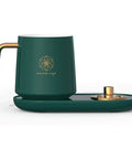 Keep Your Daily Java Straight Up Hot With This Electric Coffee Mug Warmer Boasting Five Smart Temp Settings And Auto Shut Off Across Any Desk Keeping Beverages Smooth Without The Cold Cup Blues, green mug with gold handle and base.