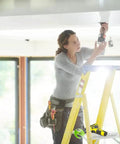 Person using Four And A Quarter Inch Carbide Hole Saw With Arbor For Recessed Lights on ceiling from ladder