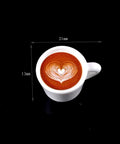 Top view of a white cup with heart latte art and dimensions 21mm x 13mm on black background.